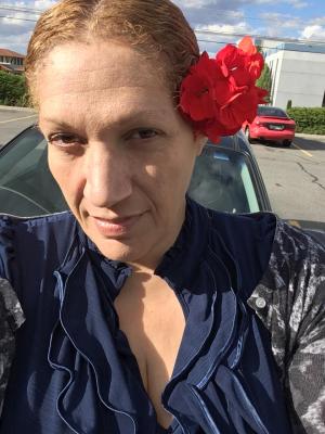 Woman in blue blouse with flower behind ear