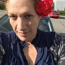 Woman in blue blouse with flower behind ear